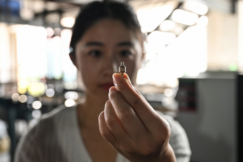 Robyn Qiu shows a small metal part that is made in the Qiu's parent metal parts factory in Nantong, in eastern China's Jiangsu province, on September 27, 2024. — AFP pic