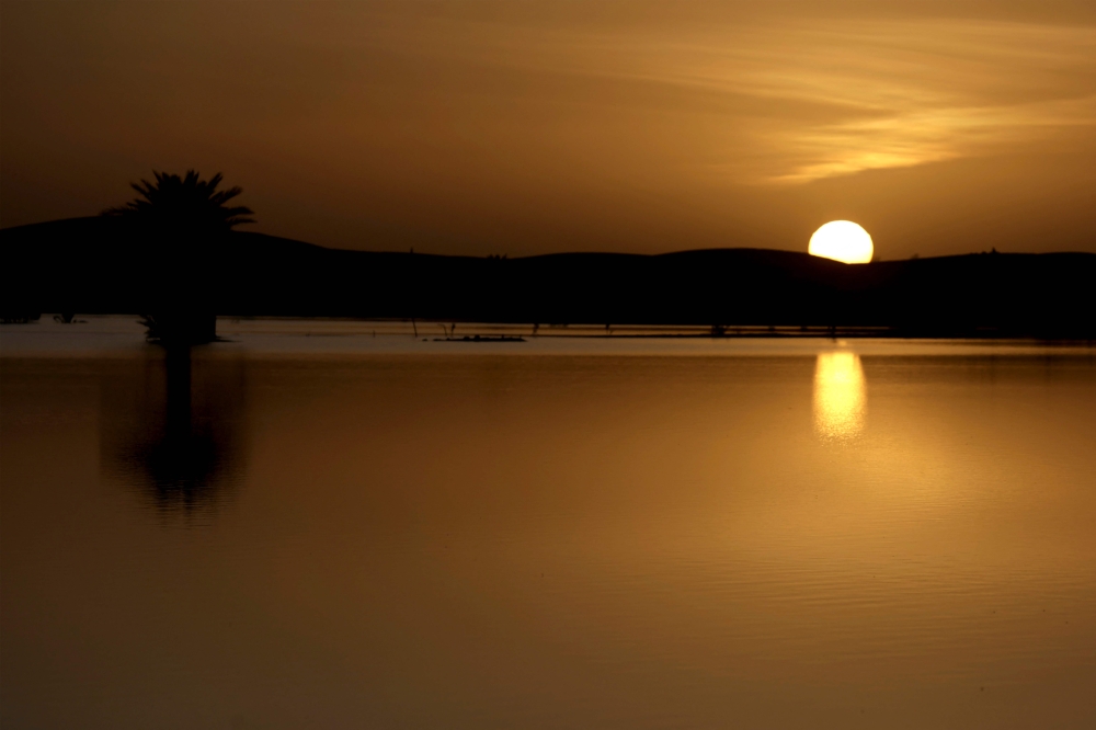 The sun sets behind the dunes at Yasmina lake, a seasonal lake in the village of Merzouga in the Sahara desert in south-eastern Morocco on October 20, 2024. — AFP pic