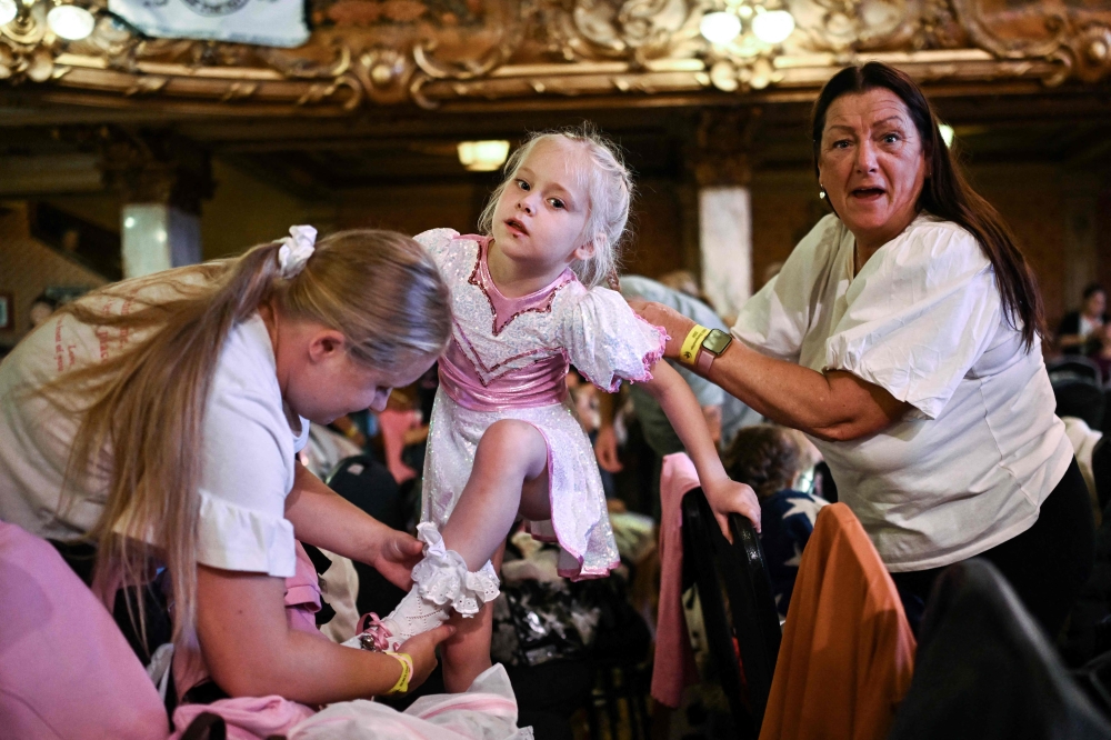 A member of the Platt Bridge Carnival Morris dancing group, performing in the Babies category, gets ready and dressed prior to compete during the Remix End of Season Championships at the Blackpool Tower Ballroom, in Blackpool September 15, 2024. — AFP pic