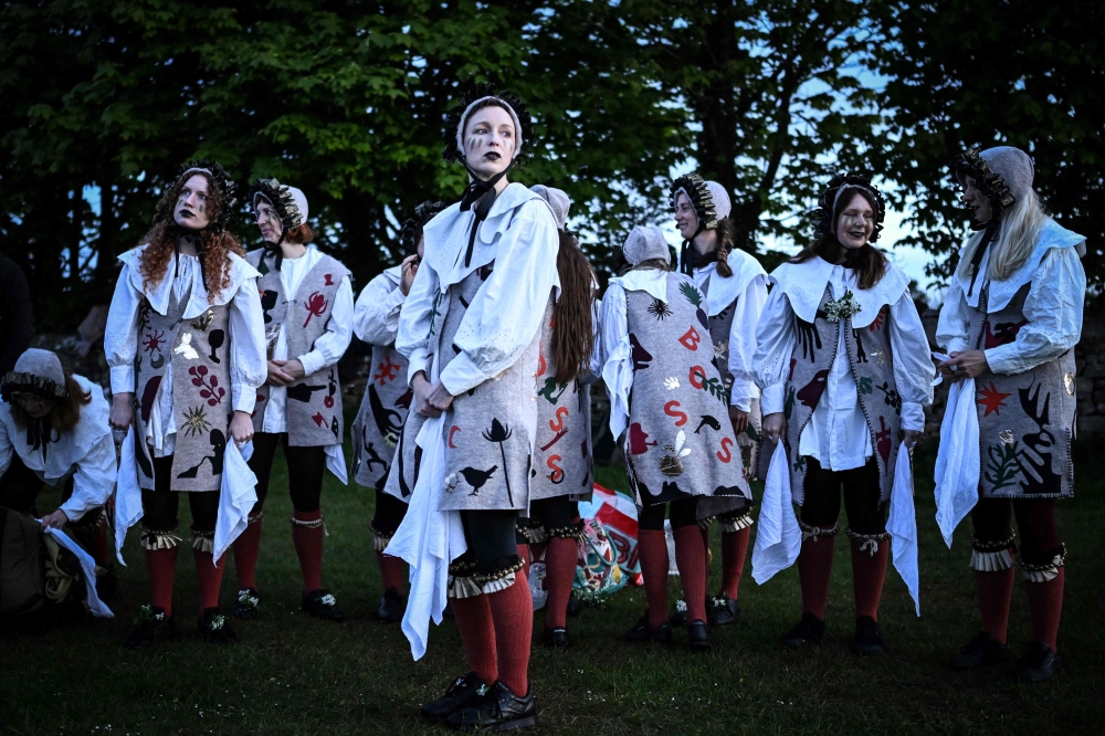 Members of Boss Morris dancing group, look on as they prepare to dance during sunrise as part of the May Day celebrations tradition, at Rodborough Common, in Stroud, west England, on May 1, 2024. Boss Morris is an only female group founded 2015 that aim at bringing Morris dancing to a new audience by mixing traditional choreographs with modern music and wearing costumes that play with folk and art. — AFP pic