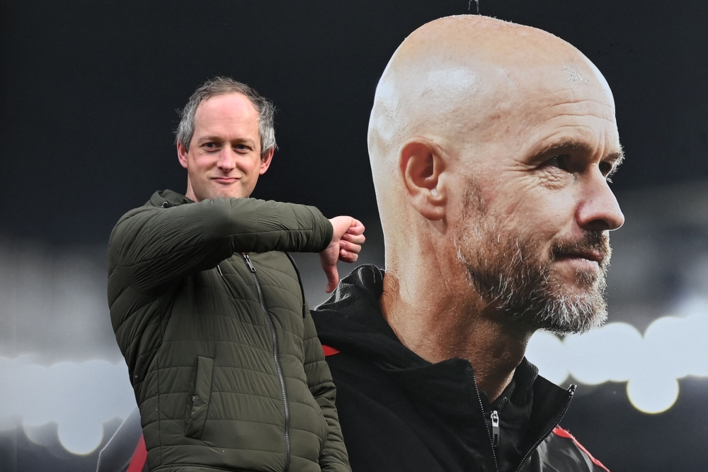 A visitor reacts as he poses in front of a picture of newly sacked Manchester United's Dutch manager Erik ten Hag, outside Old Trafford, in Manchester, north west England, on October 28, 2024. — AFP pic