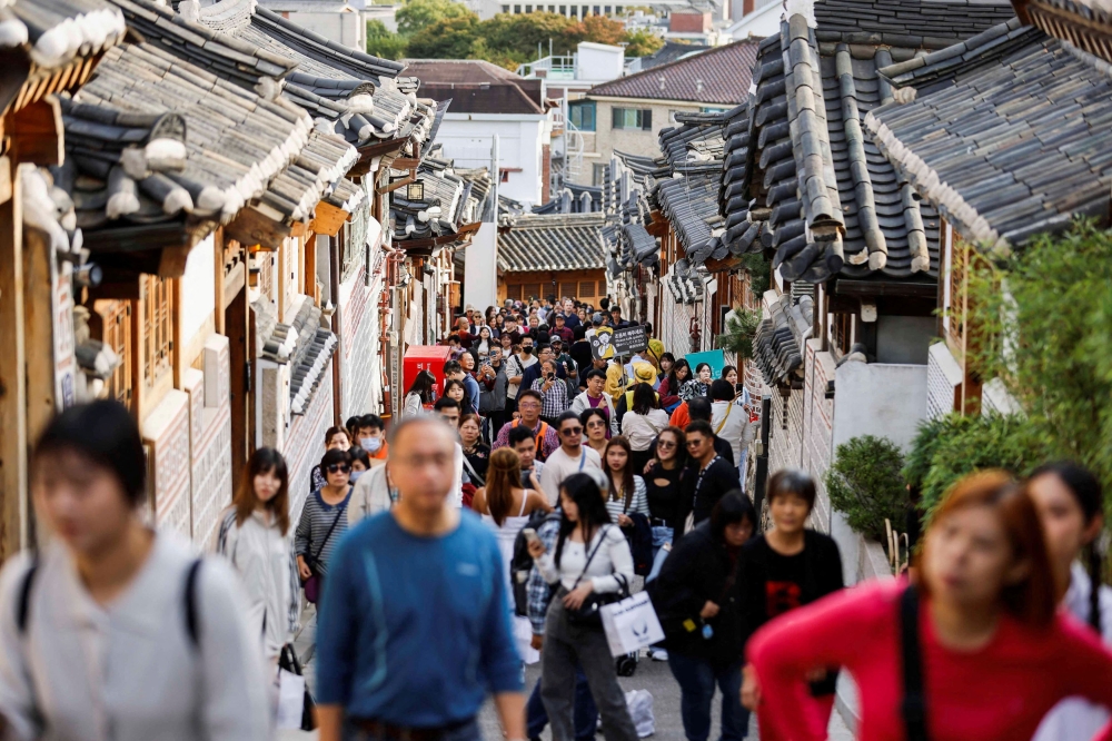 A large crowd of tourists walks through Bukchon Hanok Village. — Reuters pic