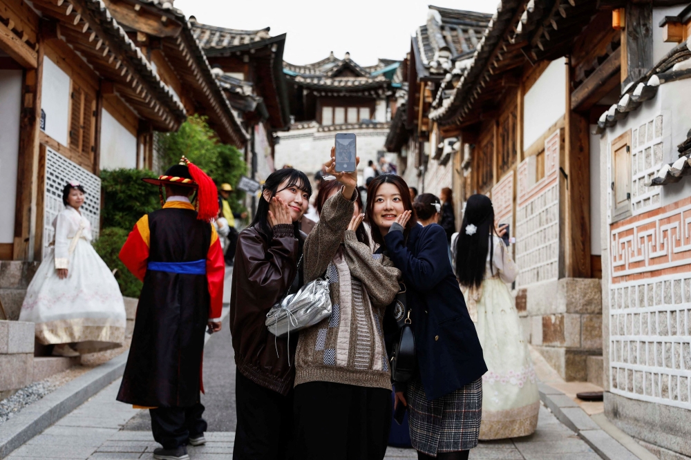 Tourists take selfies at Bukchon Hanok Village. — Reuters pic