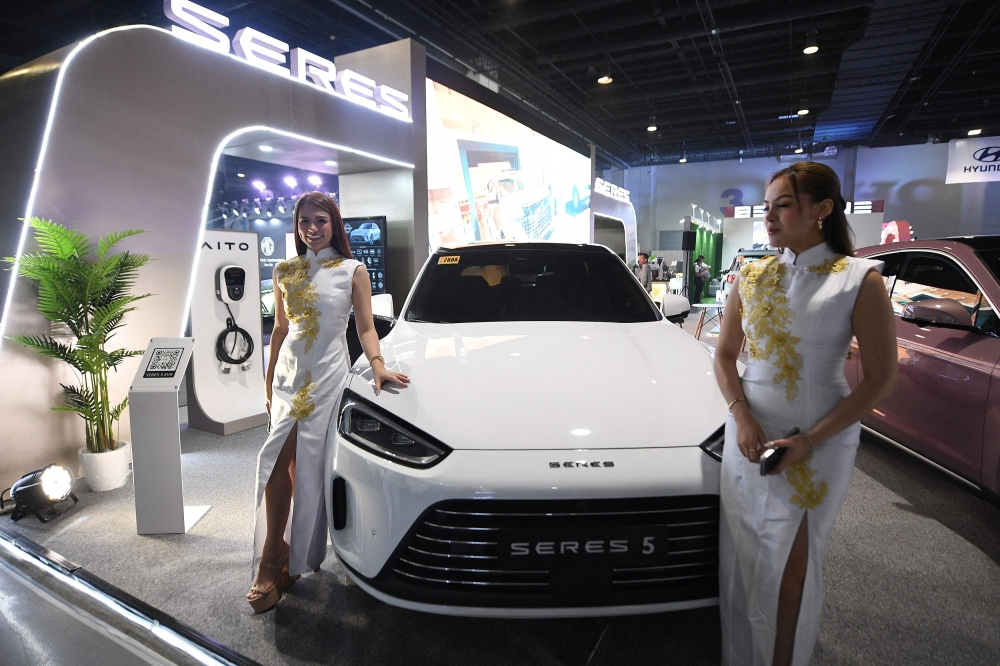 A model stands next to an electric vehicle of China's Seres at the Philippine Electric Vehicle Summit in Manila on October 24, 2024. — AFP pic