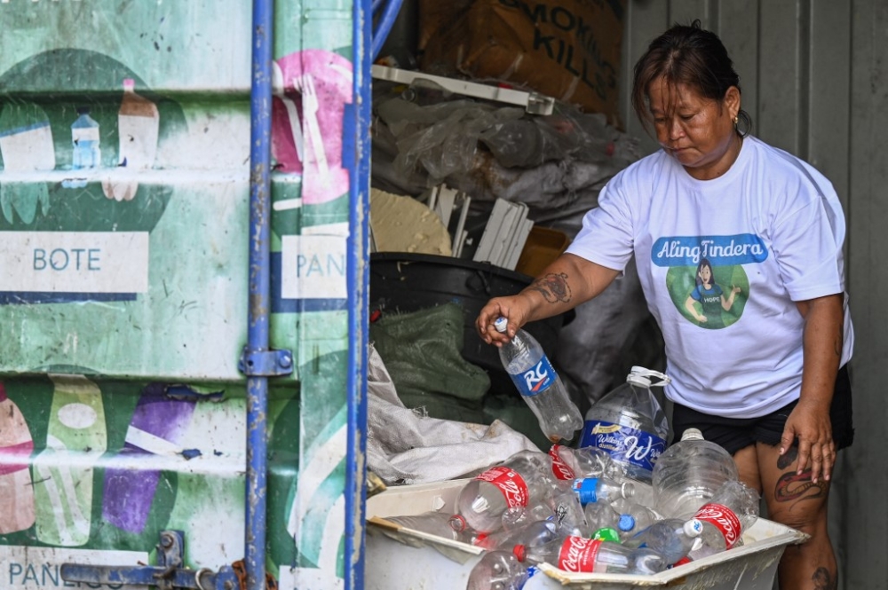 This photo taken on October 16, 2024 shows Marita Blanco, who buys plastic bottles, styrofoam and candy wrappers for two pesos (RM0.15) a kilogramme to be resold at a 25 per cent markup to US charity Friends of Hope in its waste-to-cash programme, sorting plastic bottles in Manila. v