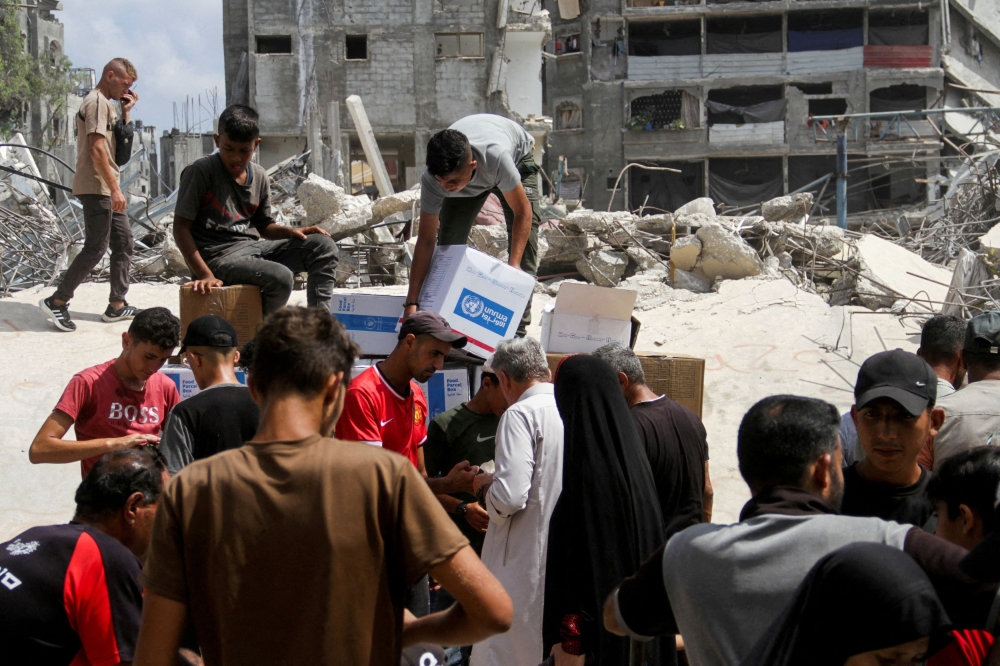  Palestinians gather to receive aid, including food supplies provided by the World Food Program, outside a United Nations distribution center, amid the Israel-Hamas conflict, in Jabalia in the northern Gaza Strip, August 24, 2024. — Reuters pic  