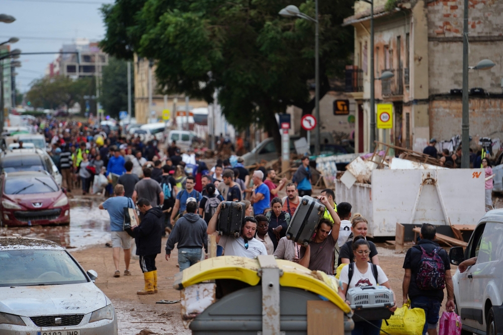 Residents walk in the street while transporting belongings following deadly flash floods in La Torre, south of Valencia, eastern Spain, on October 31, 2024. — AFP pic 