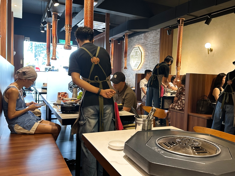 Each table has their own personal octagonal grill for the server to prepare the chosen chicken meat or spare parts in front of you. — Picture by Lee Khang Yi