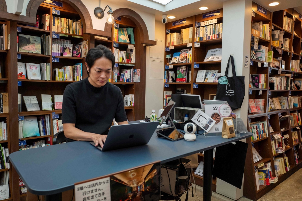 This photo taken on August 1, 2024 shows Rokurou Yui, president of book review site All Reviews and president of three shelf-sharing bookstores, working at his bookstore in Tokyo’s Kanda Jimbocho district, one of the world’s largest ‘booktowns’.— AFP pic 