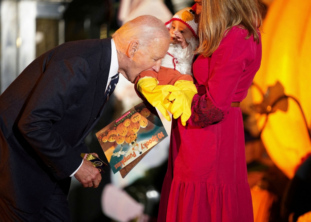 US President Joe Biden playfully bites a baby during a trick-or-treaters celebration at the White House in Washington, US, October 30, 2024. — Reuters pic