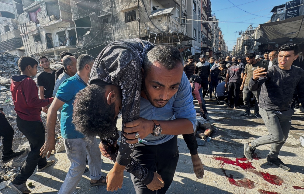 A Palestinian carries an injured person following an Israeli strike, amid the Israel-Hamas conflict, in Beit Lahiya in the northern Gaza Strip October 30, 2024. — Reuters pic