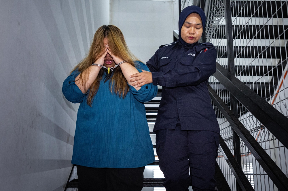 Siti Nuridah Jumli shields her face from the cameras as she is brought to the Magistrate’s Court in Ipoh November 4, 2024. — Bernama pic