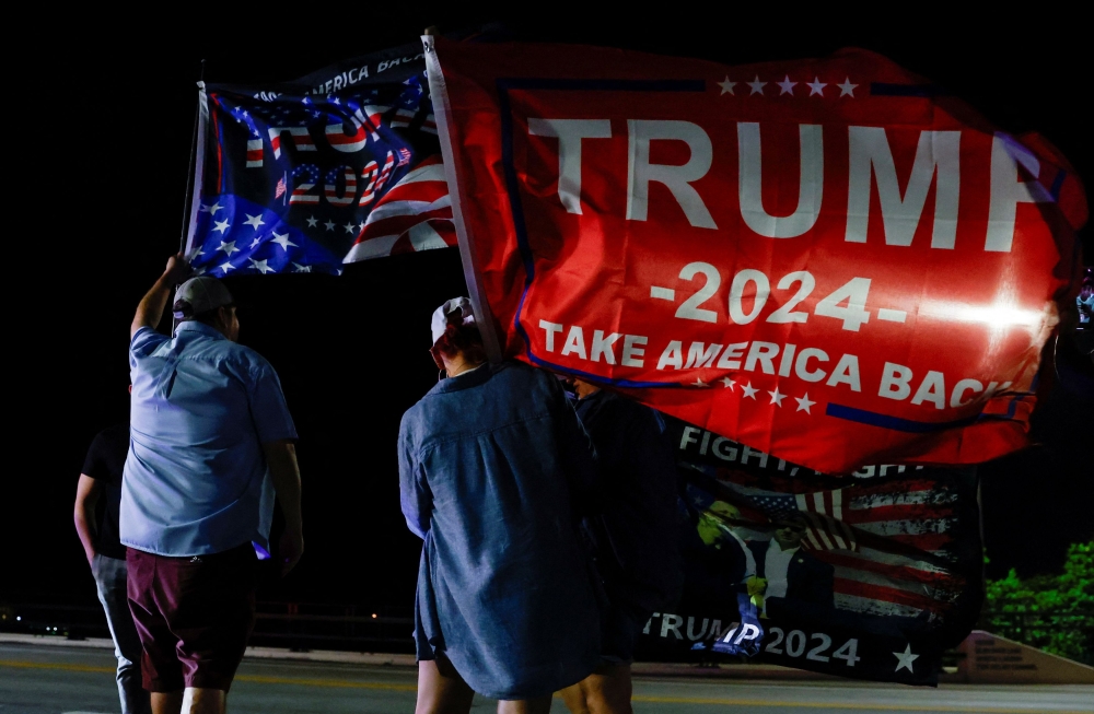 Supporters of Republican presidential nominee and former US president Donald Trump hold flags on Election Day, near Mar-a-Lago, in Palm Beach, Florida, November 5, 2024. — Reuters pic