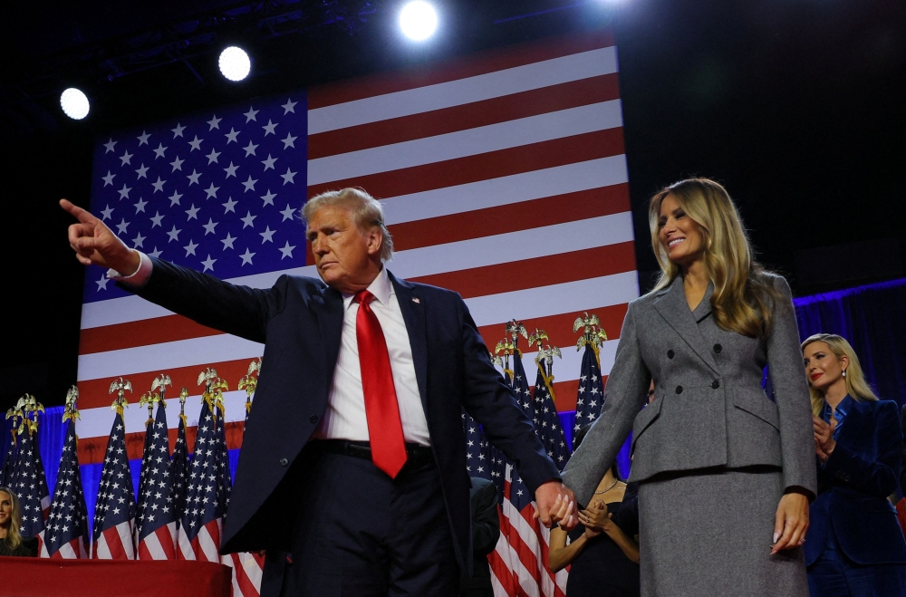 Republican presidential nominee and former US president Donald Trump gestures as he holds hands with his wife Melania during his rally in West Palm Beach, Florida, November 6, 2024. — Reuters pic