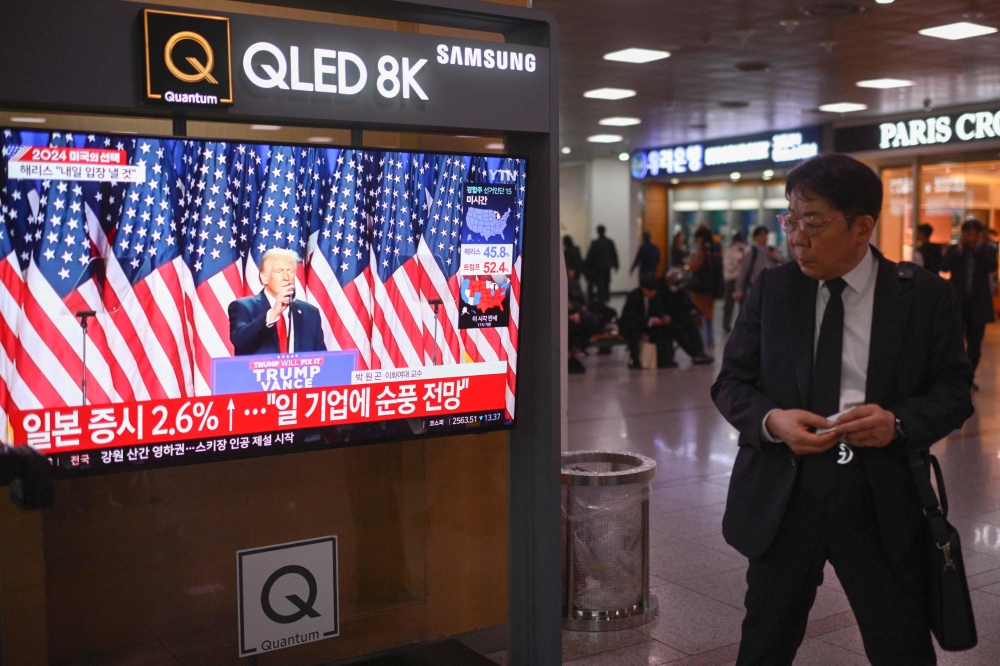 A man pauses to watch a television broadcasting footage of former US president and Republican presidential candidate Donald Trump as he speaks during an election night event, at a train station in Seoul November 6, 2024. — AFP pic