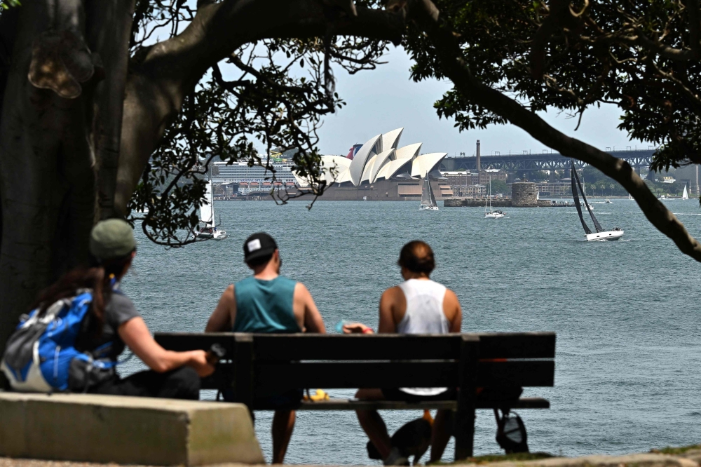 Visitors spend their morning under a large tree at Bradleys Head in Sydney, overlooking the Opera House on November 3, 2024, as spring transitions into summer with a high temperature of 33 degrees Celsius. — AFP pic