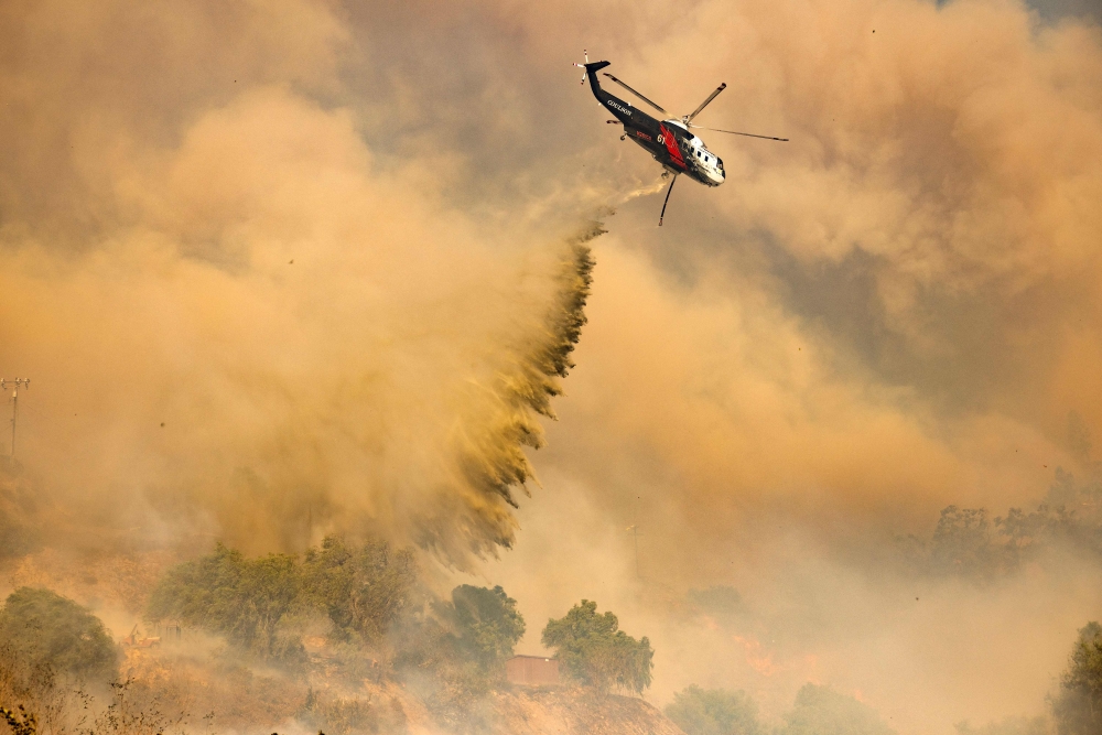 A firefighting helicopter makes drop over the Mountain Fire in Camarillo Heights, Camarillo, California, on November 6, 2024. A wildfire fanned by powerful winds was burning out of control near Los Angeles, with scores of residents ordered to evacuate and some taken to hospital. — AFP pic