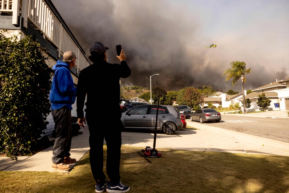 Residents watch a firefighting helicopter flying over the burning hills as the Santa Ana wind-fed Mountain fire scorches acres, in Camarillo, California November 6, 2024. Fierce gusts up to 80 miles (130 kilometres) an hour were pushing smoke sideways and fueling flames that were tearing through farmland. — AFP pic