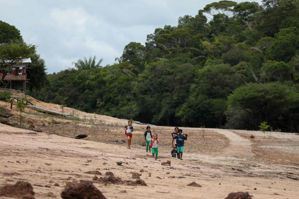 Children walk on a sandbank on their way to school in Santo Antonio Community in Novo Airao, Amazonas state October 1, 2024. More than 420,000 children in the Amazon basin are being badly affected by a drought parching much of South America that is impacting water supplies and river transport, Unicef said yesterday. — AFP pic