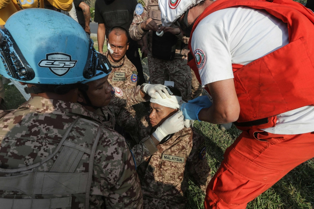 A rescuer and a member of the Malaysian battalion of the United Nations Interim Force In Lebanon (UNIFIL) treat the wound of a fellow soldier, after he was injured at the site of an Israeli airstrike at the northern entrance of the southern Lebanese city of Sidon, on November 7, 2024. — AFP pic