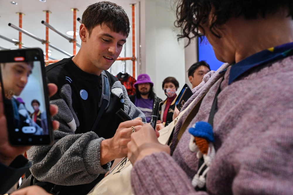 Retired British Olympic diving champion Tom Daley (L) signs an autograph for fans as he arrives at a new exhibition showcasing knitting creations he has made since taking up the craft in 2020, in the Shibuya district of central Tokyo on November 8. — AFP pic