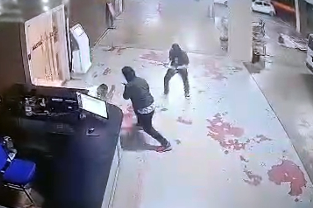 Screengrab from the CCTV footage of the hotel during the shooting shows two suspects and the victim on the floor. — The Borneo Post pic