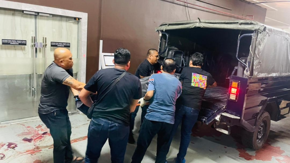 Police personnel move the victim's body into a vehicle. — Photo courtesy of Bintulu Police