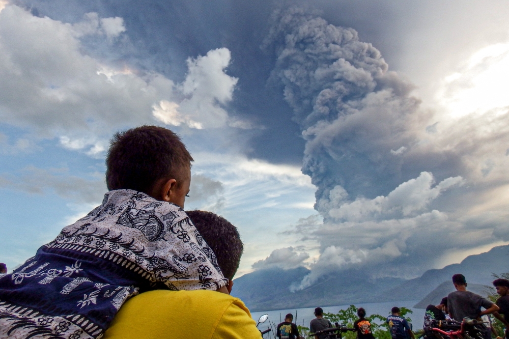 Residents watch the eruption of Mount Lewotobi Laki-Laki from Eputobi village in Titihena, East Nusa Tenggara, November 8, 2024. — AFP pic