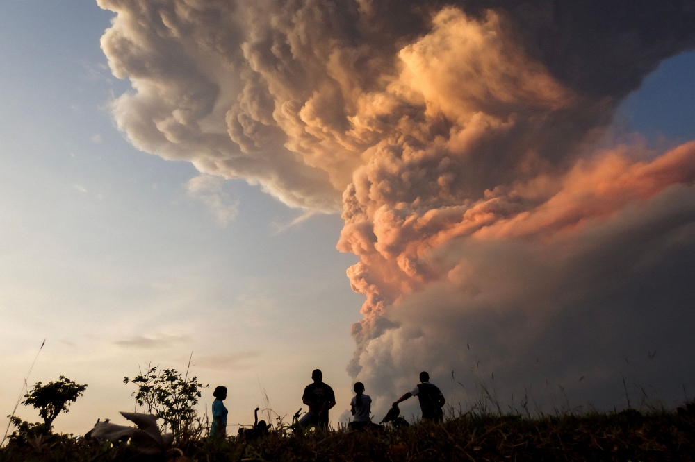 Residents watch the eruption of Mount Lewotobi Laki Laki from Lewolaga village in East Flores, East Nusa Tenggara earlier today. — AFP