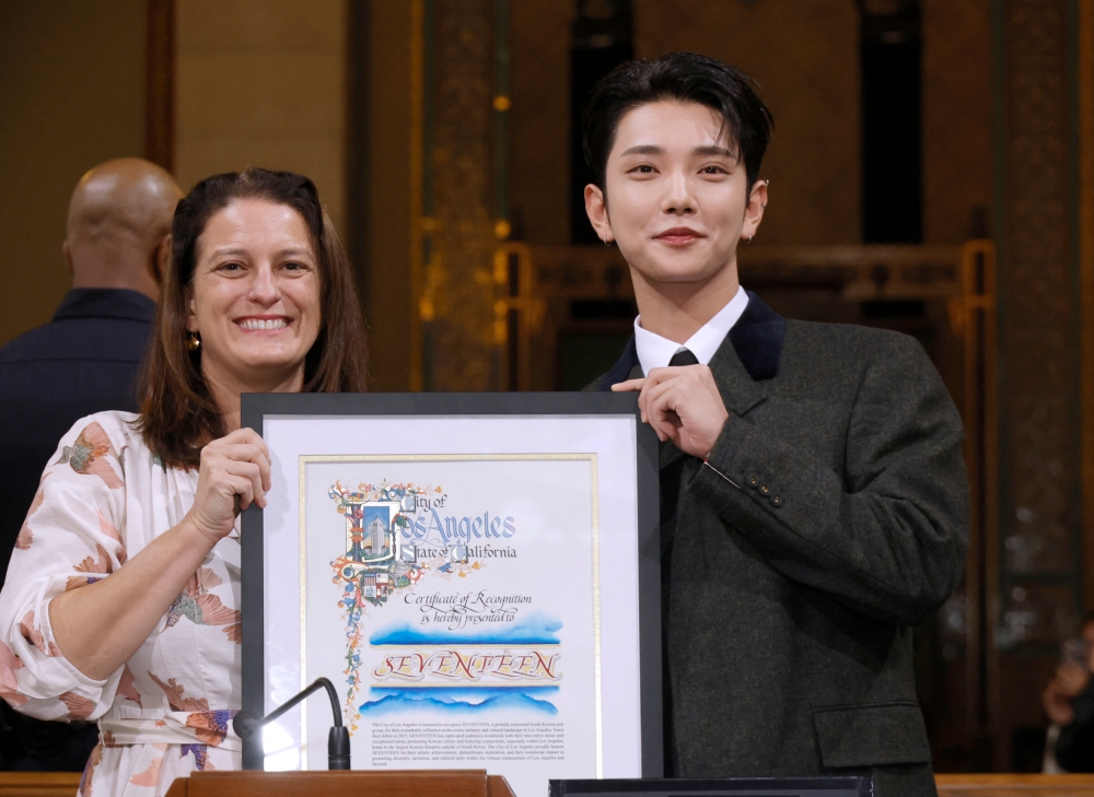 Seventeen group member Joshua Hong (Right) accepts on behalf of the band a certificate of recognition from Councilwoman Katy Yaroslavsky honoring the K-Pop Group Seventeen during the Los Angeles City Council Meeting at Los Angeles City Hall on November 08, 2024 in Los Angeles, California. — Getty Images via AFP pic