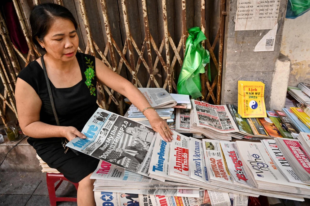 A vendor arranges Vietnamese newspapers at her stall in Hanoi on November 7, 2024, showing the reaction to the re-election of US President-elect Donald Trump. — AFP pic