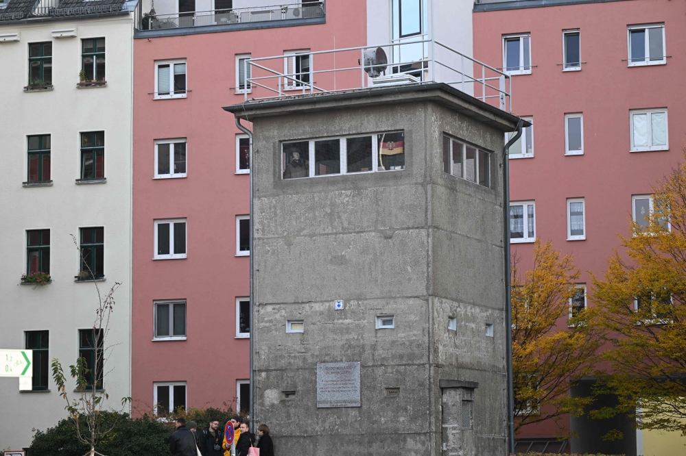 People stand in front of the German Democratic Republic (GDR) former command post that is now the Gunter Litfin memorial during the 35th anniversary of the fall of the Berlin Wall in Berlin on November 9, 2024. — AFP pic