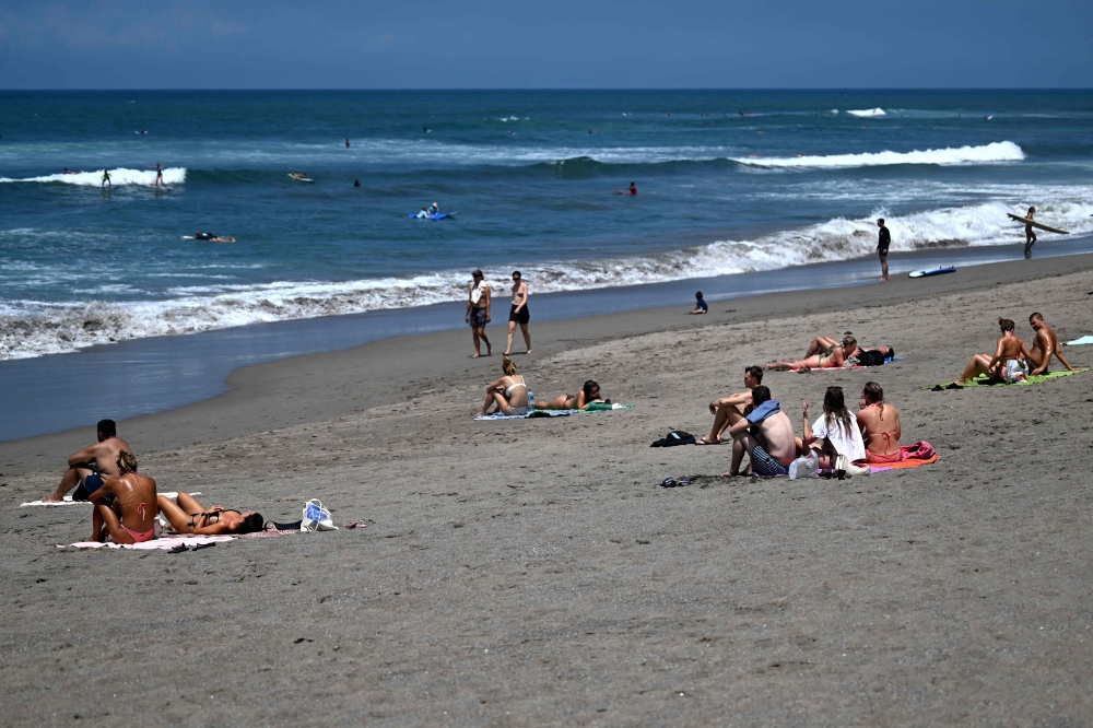 This photo taken on October 22, 2024 shows foreign tourists enjoying a beach in Canggu, Badung regency on Bali island. — AFP pic