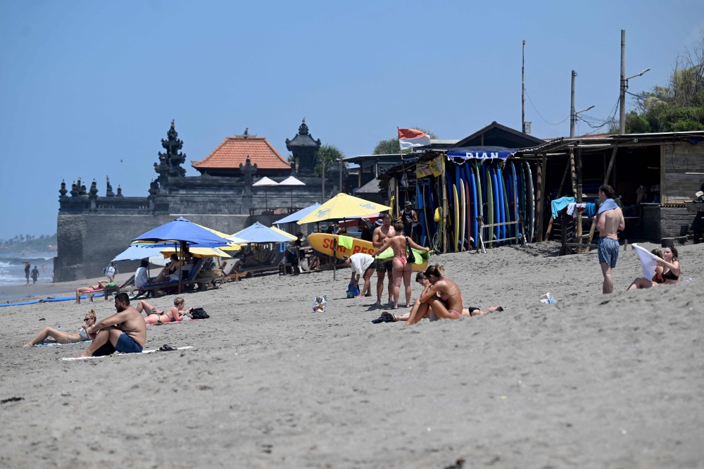 This photo taken on October 22, 2024 shows foreign tourists enjoying a beach in Canggu, Badung regency on Bali island. On Indonesia’s beach-fringed resort island of Bali, fed-up locals want to slow the mass tourism that is their biggest money earner — hoping a plan to freeze hotel-building can restore some calm. — AFP pic