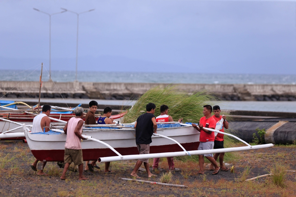 Residents and fishermen carry a wooden fishing boat to a safer place at a village in Legaspi City, Albay province, south of Manila on November 16, 2024, ahead of Super Typhoon Man-yi's landfall. All vessels — from fishing boats to oil tankers — have been ordered to stay in port or return to shore. — AFP pic