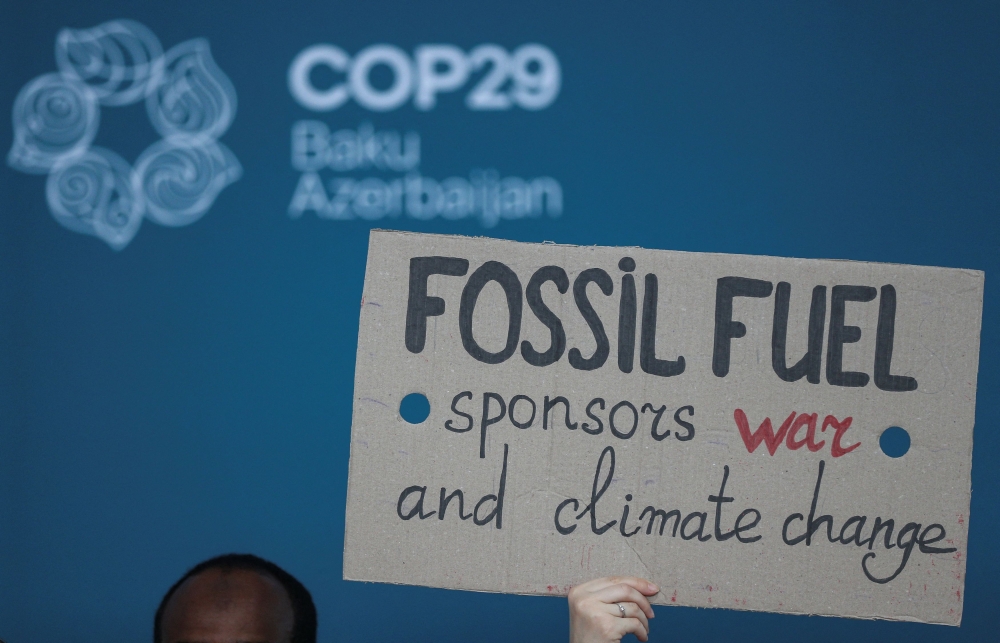 An environmental activist holds a placard as they protest against the continued use of fossil fuels during the United Nations Climate Change Conference (COP29), in Baku, Azerbaijan November 14, 2024. — Reuters pic