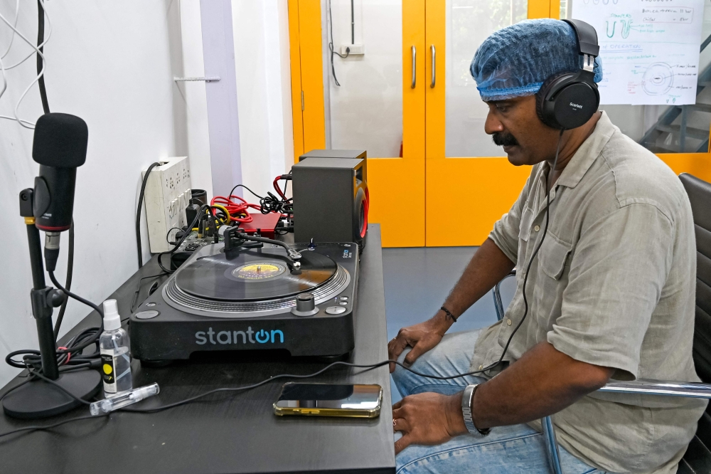 In this photograph taken on September 21, 2024, founder and chief executive officer at Samanvii Digimedia Art and Solutions Saji Pillai, listens to a freshly manufactured vinyl record at a pressing plant in Navi Mumbai. — AFP pic