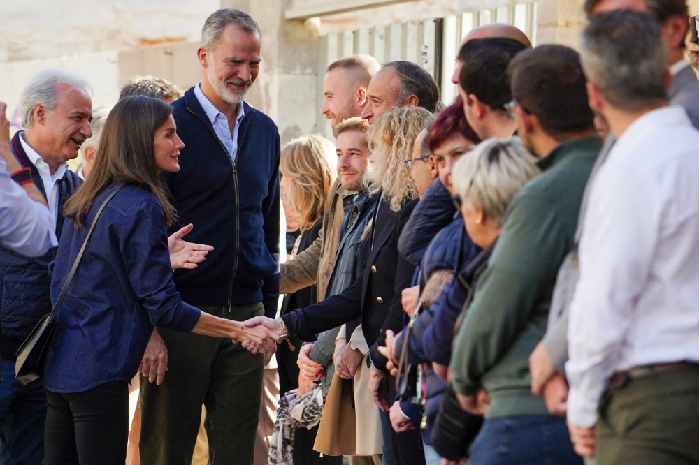 King Felipe VI and Queen Letizia (L) greet people as they visit the flood damaged town of Utiel, in the region of Valencia. — AFP pic