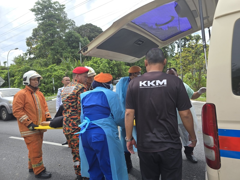 Firefighters and APM personnel carry the woman to the ambulance. — Galileo Petingi/The Borneo Post pic