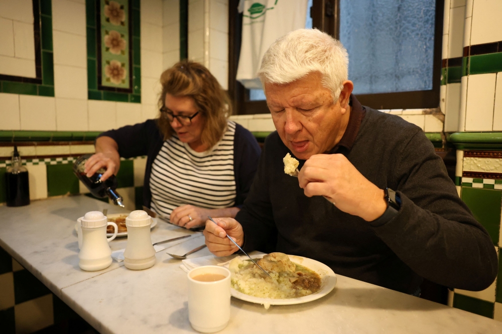 Trevor Mills and Karen Rynston, from Whitstable, eat pie and mash with liquor sauce at M. Manze, in London, Britain. — Reuters pic