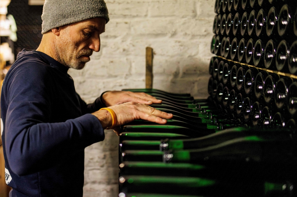 A worker checks the wall of Gueuze bottles at Cantillon brewery in Brussels. — AFP pic