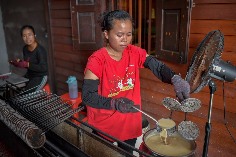 The main attraction for visitors to Ah Ma House is the opportunity to watch the traditional process of making ‘kuih kapit’, baked using charcoal. — Bernama pic