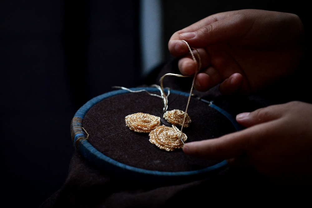 An Afghan woman embroiders on a piece of cloth at a handicraft workshop in Kabul November 10, 2024. — AFP pic