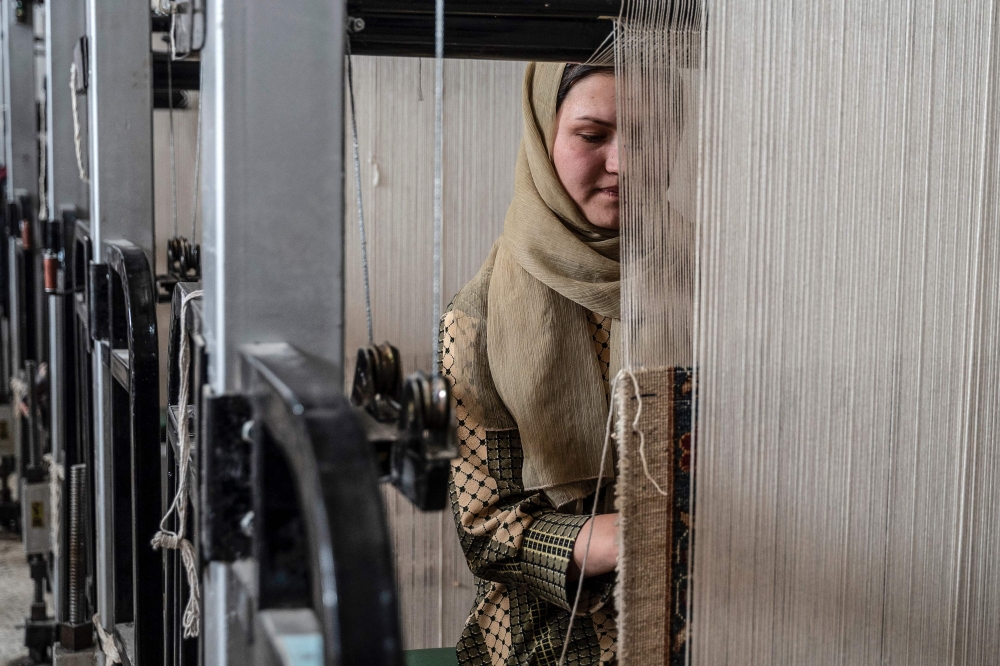 An Afghan woman weaves a carpet at a factory on the outskirts of Kabul November 11, 2024. — AFP pic