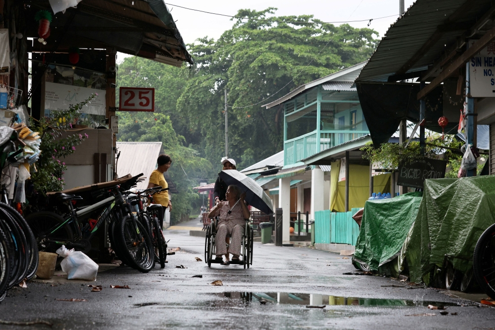 A resident and former village confectioner, known to neighbours as Tong Sau, in her 80s, chats with a shopkeeper on Singapore’s Pulau Ubin island November 1, 2024. — Reuters pic