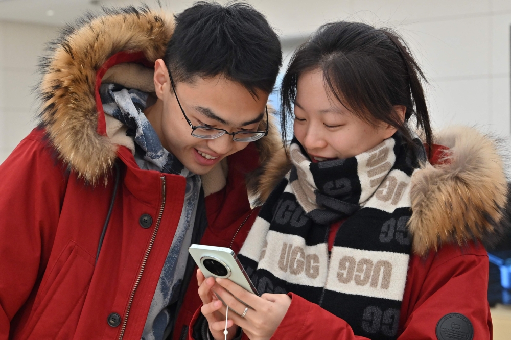 People check Huawei's new Mate 70 mobile phone inside a shop at the Wangfujing shopping area in Beijing on November 26, 2024. — AFP pic