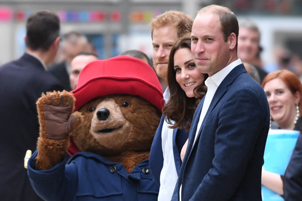 Britain’s Prince Harry (centre), Britain’s Catherine, Duchess of Cambridge (2nd right) and Britain’s Prince William, Duke of Cambridge stand by a person in a Paddington Bear outfit as they attend a charities forum event at Paddington train station in London October 16, 2017. — AFP pic