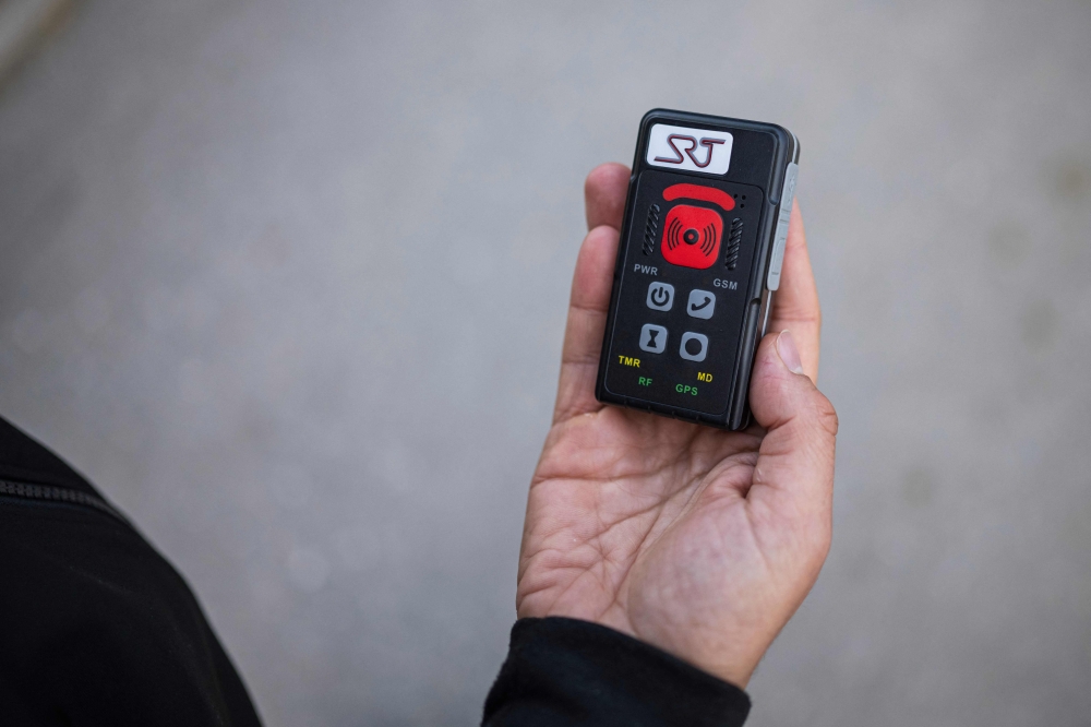 Social worker Abbe Abid shows a device made to send an SOS alarm in case of emergency as he visits the neighbourhood of Baronbackarna in Örebro, on September 23, 2024. — AFP pic