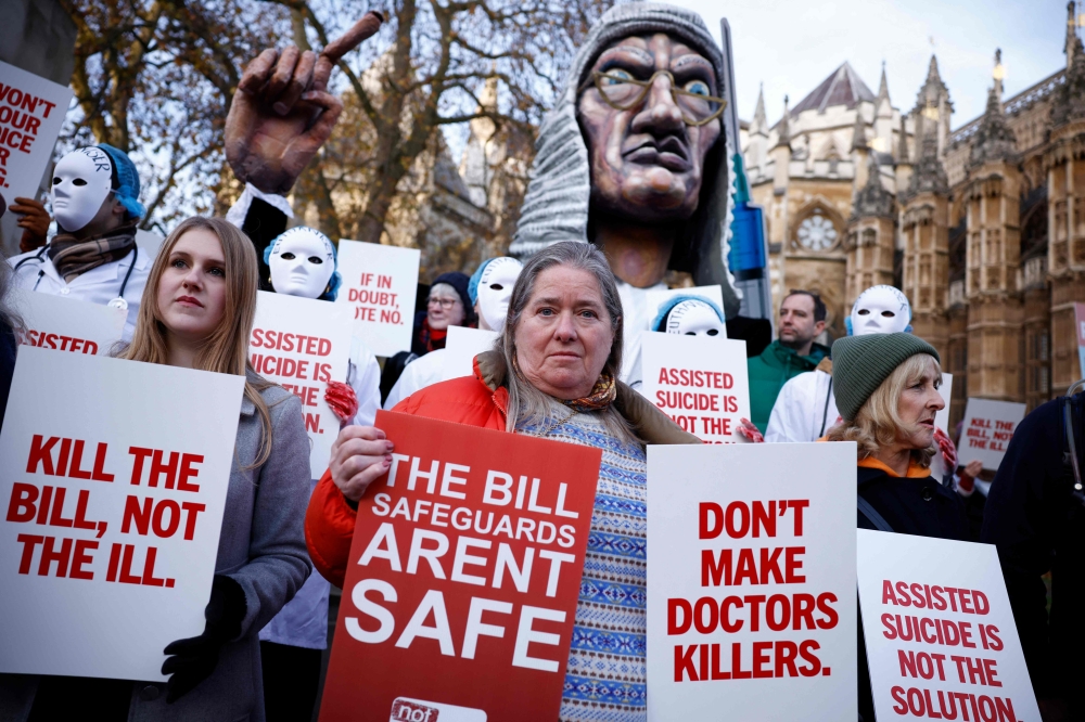 Campaigners against the assisted suicide bill hold placards at a demonstration outside The Palace of Westminster in central London, on November 29, 2024, as supporters and opponents of a bill to legalise euthanasia in the UK gather outside the Houses of Parliament while lawmakers debate the bill. — AFP pic