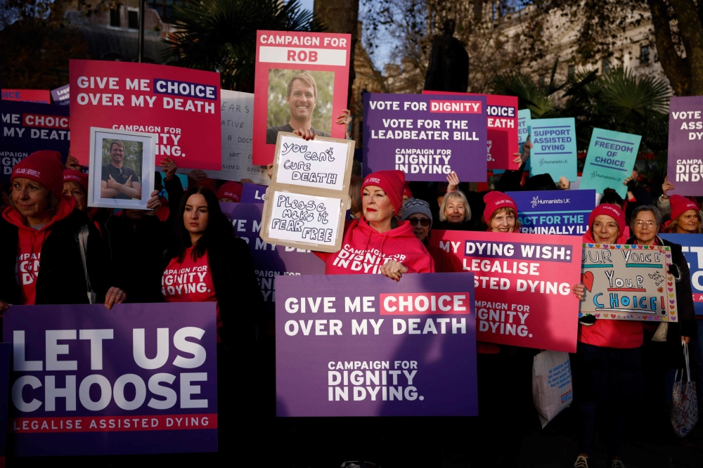 Campaigners supporting the assisted suicide bill hold placards at a demonstration outside The Palace of Westminster in central London, on November 29, 2024, as supporters and opponents of a bill to legalise euthanasia in the UK gather outside the Houses of Parliament while lawmakers debate the bill. — AFP pic